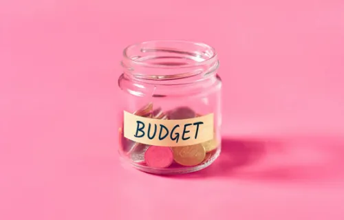 Un bocal est à moitié rempli de pièces de monnaie. Il est écrit "budget" dessus.